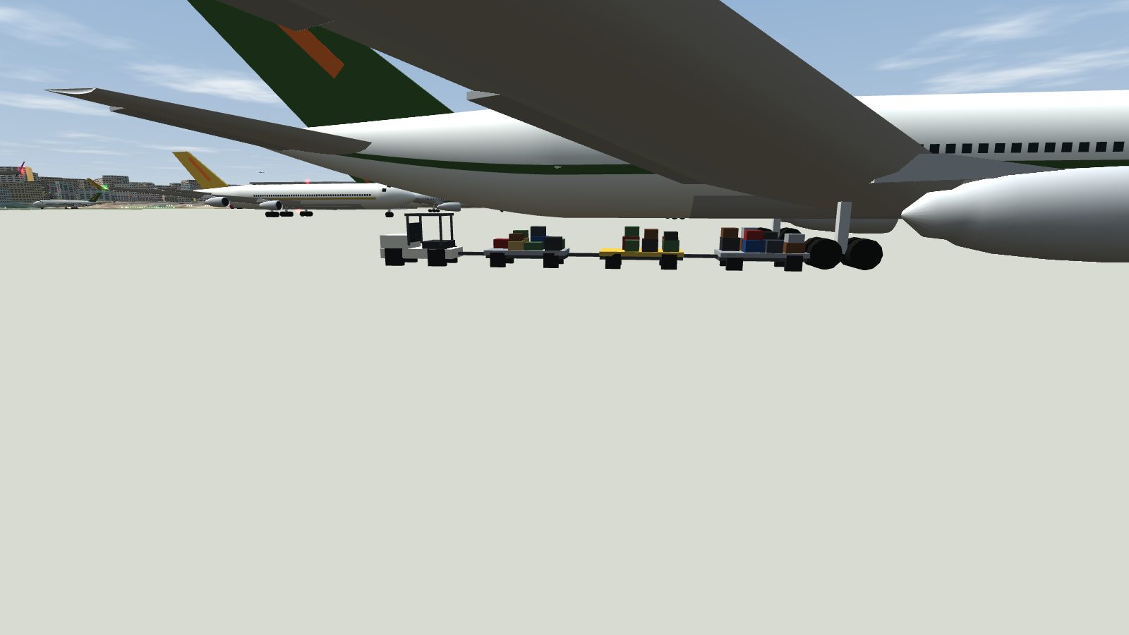 A baggage tractor towing three loaded carts under the wing of a parked aircraft.