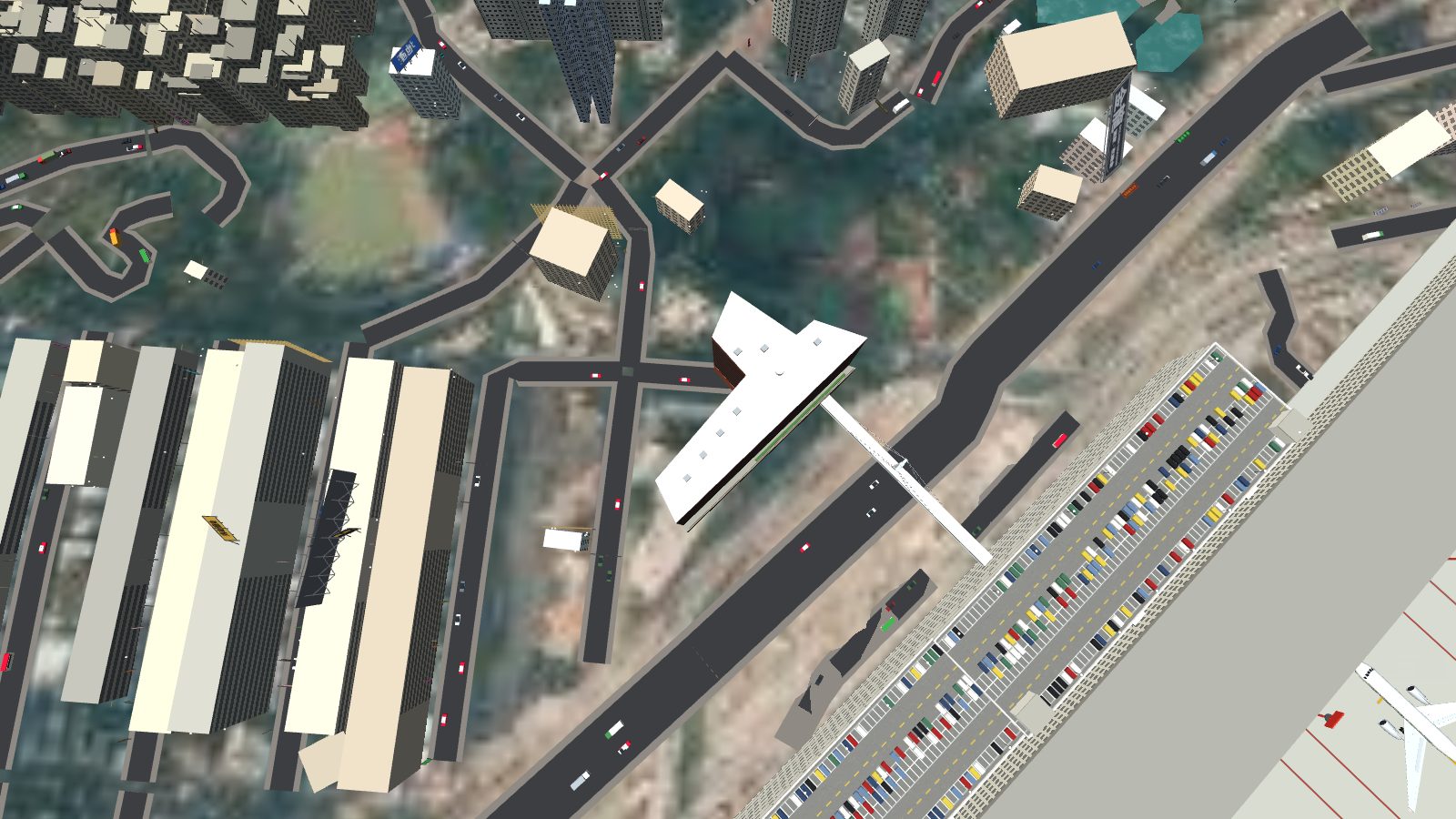 Looking straight down on the hotel roof: a long arm along the road and a wider wing at one end, the footbridge crossing the road to the car park.